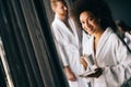 Beautiful black woman in bath robe is holding a cup and smiling while resting at hotel, spa Royalty Free Stock Photo