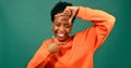 Beautiful Black woman frames face with fingers, reveal laughing portrait, studio