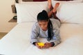Beautiful black woman in pajamas texting on her cell phone in bedroom Royalty Free Stock Photo