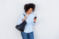 Beautiful black woman with purse looking at cellphone and laughing Royalty Free Stock Photo