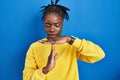 Beautiful black woman standing over blue background doing time out gesture with hands, frustrated and serious face Royalty Free Stock Photo