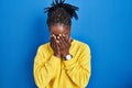 Beautiful black woman standing over blue background with sad expression covering face with hands while crying Royalty Free Stock Photo