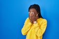 Beautiful black woman standing over blue background with sad expression covering face with hands while crying Royalty Free Stock Photo