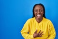 Beautiful black woman standing over blue background smiling and laughing hard out loud because funny crazy joke with hands on body Royalty Free Stock Photo