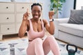 Beautiful black woman using smart watch training at home smiling with an idea or question pointing finger with happy face, number Royalty Free Stock Photo