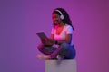 Black Woman Watching Movies On Digital Tablet While Sitting In Neon Light Royalty Free Stock Photo