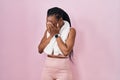 Beautiful black woman wearing sportswear and towel over pink background with sad expression covering face with hands while crying Royalty Free Stock Photo