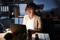 Beautiful black woman working at the office at night looking to side, relax profile pose with natural face with confident smile Royalty Free Stock Photo