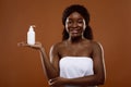 Beautiful Black Woman Wrapped In Towel Holding Bottle With Moisturising Lotion Royalty Free Stock Photo