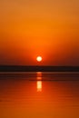 Beautiful blazing sunset landscape at the river Dnipro and orange sky above it with awesome sun golden reflection on calm water