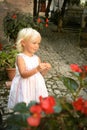 Beautiful blond blu eye caucasian baby girl in light summer dress with red flowers. Summer dreams concept. Childhood and Royalty Free Stock Photo