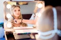 Beautiful blond bride doing makeup in her wedding day near mirror. Bride makeup.