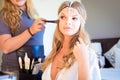 Beautiful blond bride doing makeup in her wedding day near mirror. Bride makeup.