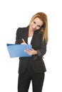 Beautiful blond businesswoman talking on mobile phone smiling writing notes on notepad folder Royalty Free Stock Photo