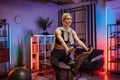 Beautiful blond caucasian sports women in sportswear cycling bike at home at night time. Royalty Free Stock Photo