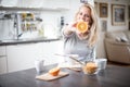 Beautiful blond caucasian woman posing in her kitchen, while drinking coffee or tea and eating a healthy breakfast meal full of ce Royalty Free Stock Photo