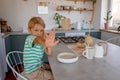 Beautiful blond child, boy, refusing to eat cereal for breakfast at home in the morning Royalty Free Stock Photo