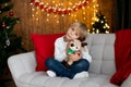 Beautiful blond child, young school boy, playing in a decorated home with knitted toys