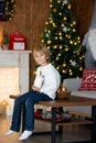 Beautiful blond child, young school boy, playing in a decorated home with knitted toys