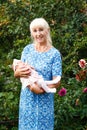 Beautiful blond elderly woman holds baby girl in her arms