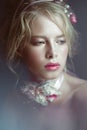 Beautiful blond fashion girl with flowers on neck and in her hair, wet Nude makeup. Beauty face. Royalty Free Stock Photo
