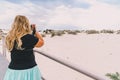 Beautiful blond female photographer takes photos on the boardwalk at the sand dunes Royalty Free Stock Photo