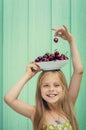 Beautiful blond girl on a background of turquoise wall holding plate with cherries her head. Royalty Free Stock Photo