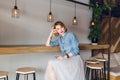 Beautiful blond girl with blue eyes and bright pink lips sitting in a coffee shop on a chair. She wears blue denim shirt Royalty Free Stock Photo