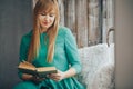 Beautiful blond girl with a book in her hands looking out the window Royalty Free Stock Photo