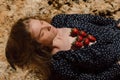 Beautiful blond girl with closed eyes lies on earth with strawberry Royalty Free Stock Photo