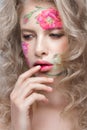 Beautiful blond girl with curls and a floral pattern on the face. Beauty flowers.