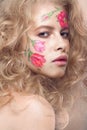 Beautiful blond girl with curls and a floral pattern on the face. Beauty flowers. Royalty Free Stock Photo