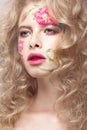 Beautiful blond girl with curls and a floral pattern on the face. Beauty flowers. Royalty Free Stock Photo