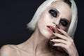 Beautiful blond girl with dark smokey makeup and art manicure design nails. beauty face.