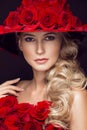 Beautiful blond girl in dress and hat with roses, classic makeup, curls, red lips. Beauty face. Royalty Free Stock Photo