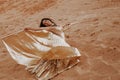 A beautiful girl in a golden with brilliant dress with wings, suit is dancing an oriental, East dance in the desert Royalty Free Stock Photo