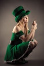 Beautiful blond girl in leprechaun clothes sitting with a coin
