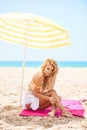 Beautiful blond girl sitting on the beach Royalty Free Stock Photo