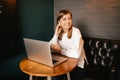 Beautiful blond girl sitting in cafe with laptop, smiling at camera Royalty Free Stock Photo