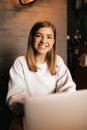 Beautiful blond girl sitting in cafe with laptop, smiling at camera Royalty Free Stock Photo