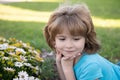 Beautiful blond little child boy with long hair smelling flower. Spring child face. Funny kids face. Happy little blond Royalty Free Stock Photo