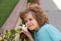 Beautiful blond little child with long hair smelling flower. Spring child face. Funny kids face. Happy little blond hair Royalty Free Stock Photo