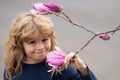 Beautiful blond little child with long hair smelling flower. Spring child face. Funny kids face. Happy little blond hair Royalty Free Stock Photo