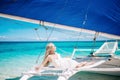 Beautiful blond long hair bride in white dress. She lay on the blue sailboat. Blue sky and turquoise sea on the background Royalty Free Stock Photo