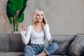 Beautiful blond pensive girl sitting on the sofa and talking on the phone Royalty Free Stock Photo