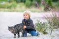 Beautiful blond toddler child with little cat on the beach, hugging, friendship between kid and kitten Royalty Free Stock Photo