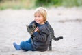 Beautiful blond toddler child with little cat on the beach, hugging, friendship between kid and kitten Royalty Free Stock Photo