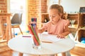 Beautiful blond toddler girl drawing with colored pencils at kindergarten Royalty Free Stock Photo