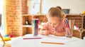 Beautiful blond toddler girl drawing with colored pencils at kindergarten Royalty Free Stock Photo