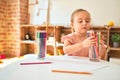 Beautiful blond toddler girl drawing with colored pencils at kindergarten Royalty Free Stock Photo